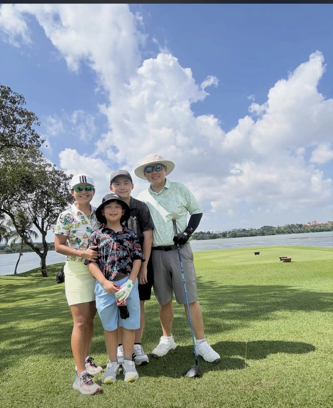 a family of 4 learning golf together on the golf course with clubs